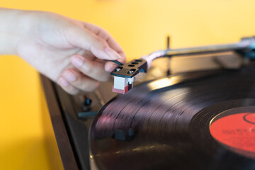 Close up woman hand put the needle on a record, playing vinyl disc at the party. Female dropping the needle on a long playing vinyl record. Music on vinyl discs.