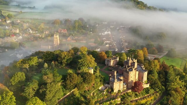 Aerial of Dunster Castle emerging from morning mist in Exmoor, Somerset, England