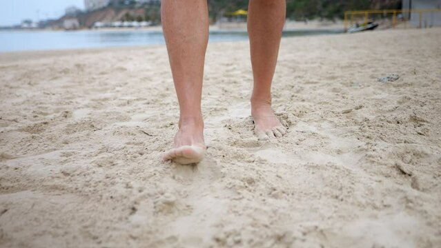 Barefooted person treading carefully on sand using heel and soles of feet