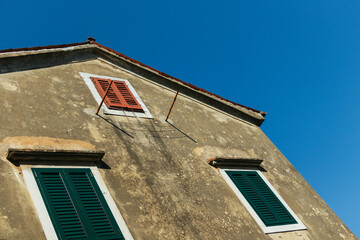 The Sunlit Facade: Croatian Old House with Colorful Shutters and Contrasting Shadows
