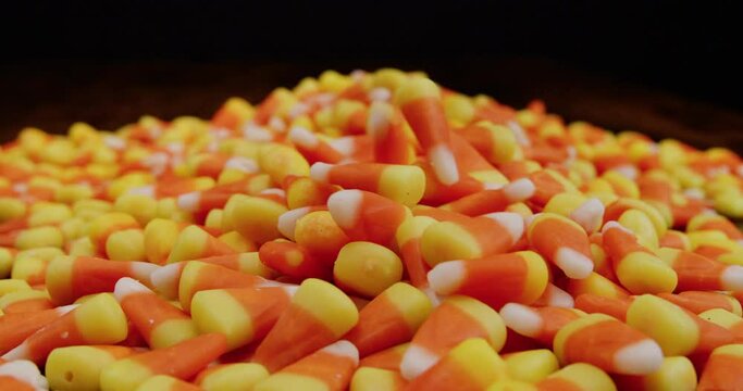Candy corn falling into  pile in slow motion in wide static shot
