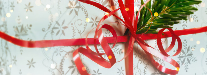festive wrapped christmas gift box with red ribbon and green fir tree branch decoration for coupon...