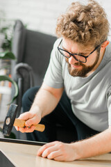 Bearded millennial man assemble his bookcase. He uses tools for furniture. Furniture for the interior room or apartments