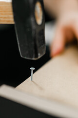 Hammering a nail into wooden board close-up