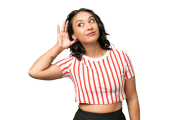 Young Argentinian woman over isolated background listening to something by putting hand on the ear