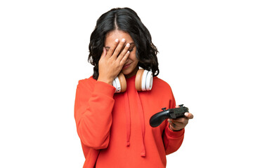 Young Argentinian woman playing with a video game controller over isolated background with tired and sick expression © luismolinero