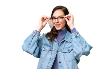 Young caucasian woman wearing winter muffs over isolated background with glasses and surprised
