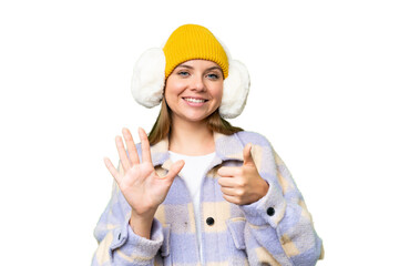 Young blonde woman wearing winter muffs over isolated chroma key background counting six with fingers