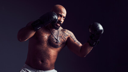 Fototapeta na wymiar Mixed-race man threw a punch in the air with boxing gloves in a studio shot