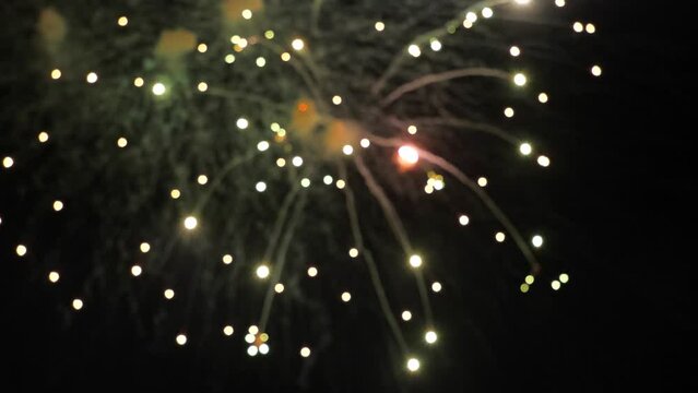 Sparkling fireworks bursts glow in black night sky on holiday blurry view