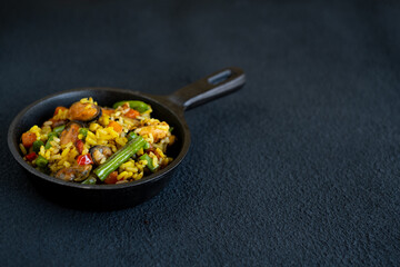 Seafood risotto in a pan on a black background