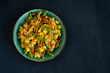 Risotto with seafood and vegetables on black background
