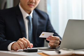 Businessman hand holding credit card and using laptop. E-commerce, online shopping, internet banking concept