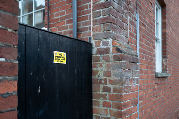 Small No Parking sign seen on a side gate of a private house. Located down a narrow street, to help prevent vehicles from blocking access.