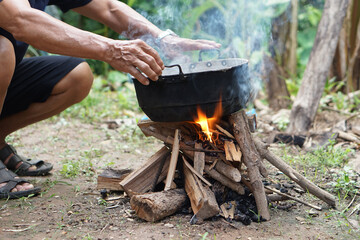 Close up man holds old black pot to cook on bonfire. Concept, cooking outdoor, kitchen in forest....