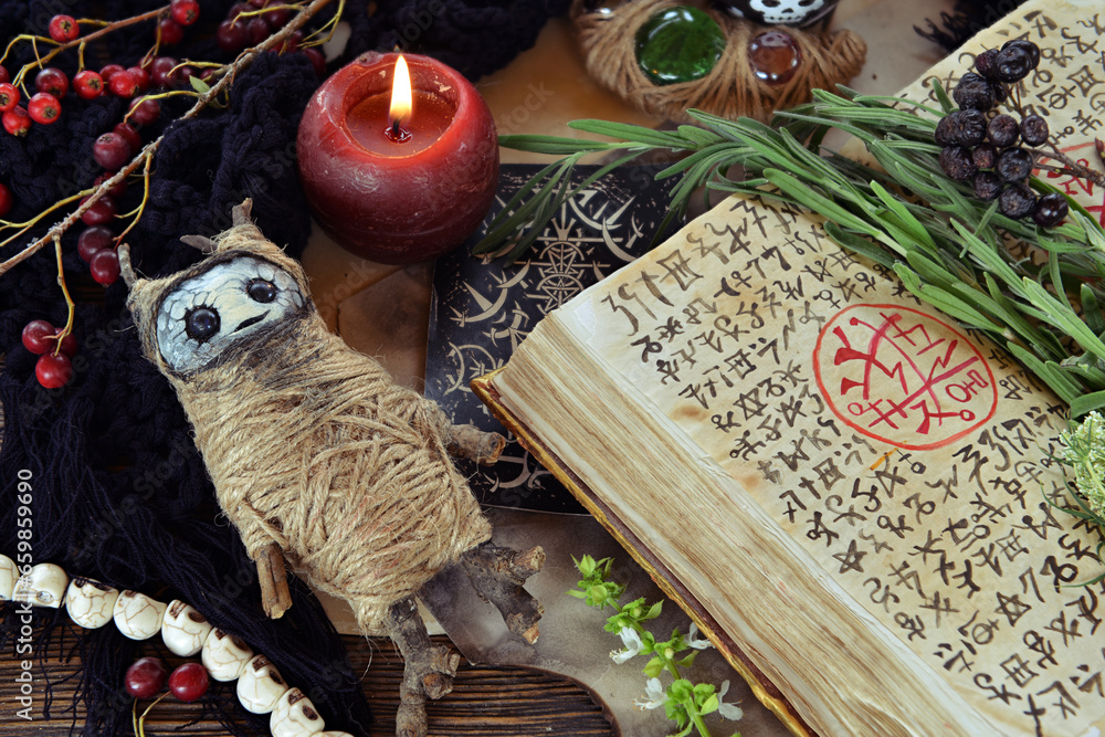 Sticker Book of spell with candles and voodoo doll on witch table. No foreign language, only fantasy symbols. Occult, esoteric and divination still life. Mystic Halloween background with vintage objects