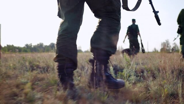 Squad of armed soldiers patrol border line with service dog, special security forces control boundary zone. Trail action and operation against enemy invasion at military facility