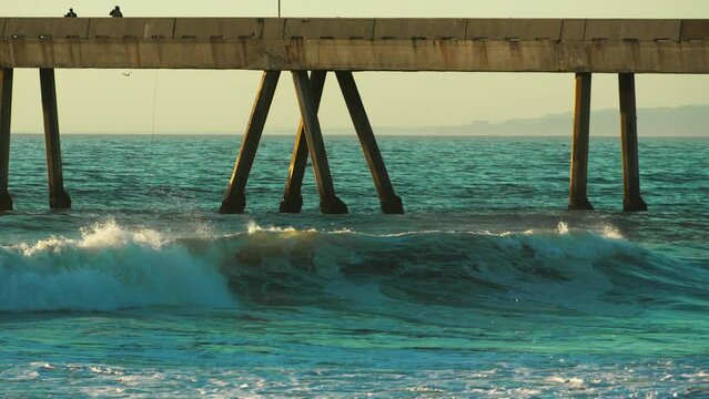 Waves crashing under pier in slow motion 