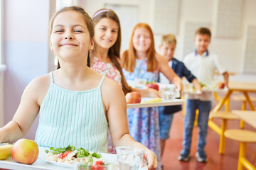 Smiling students standing in line holding food trays