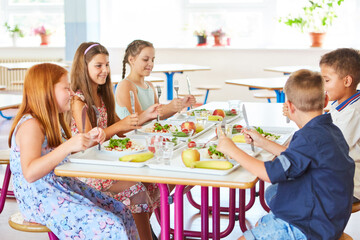 Students holding cutlery sitting at table in canteen