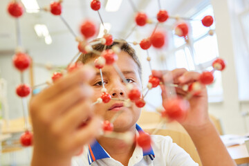 Boy examining molecular structure in classroom at school - Powered by Adobe