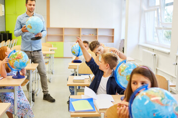 Elementary school teacher teaching class of children in geography