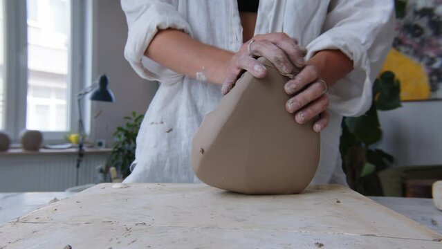 Women's hands knead the tight clay for the work on the potter's wheel. The handiwork of a woman's hard work. Women artists are creating, achieving success, feminism in action. Close-up slow motion 120