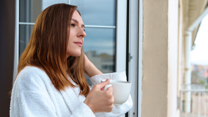 The morning starts with a cup of coffee. A young woman is resting on the balcony.