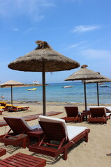 Sonnenschirme aus Stroh und Strandliegen am Strand