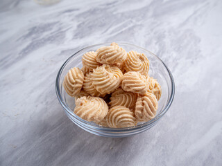 Sago Cookies are neatly presented in a white bowl with an attractive arrangement. They are isolated against a white background in a dining table setting.