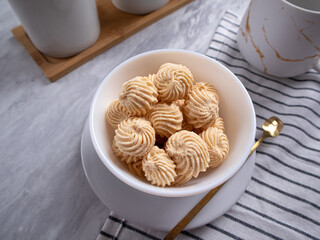 Sago Cookies are neatly presented in a white bowl with an attractive arrangement. They are isolated against a white background in a dining table setting.