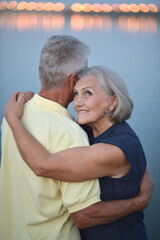 Portrait of beautiful senior couple hugging on a lilac background in the park