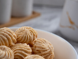 Sago Cookies are neatly presented in a white bowl with an attractive arrangement. They are isolated against a white background in a dining table setting.
