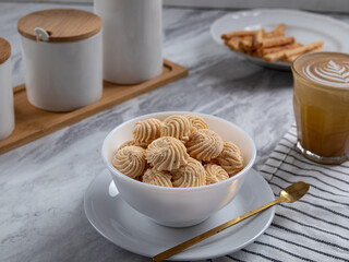 Sago Cookies are neatly presented in a white bowl with an attractive arrangement. They are isolated against a white background in a dining table setting.