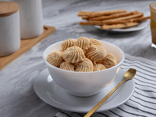 Sago Cookies are neatly presented in a white bowl with an attractive arrangement. They are isolated against a white background in a dining table setting.