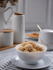 Sago Cookies are neatly presented in a white bowl with an attractive arrangement. They are isolated against a white background in a dining table setting.