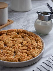 Kue Kastengel or Kaastangels are neatly presented on a white plate with attractive decorations. They are isolated against a kitchen background.