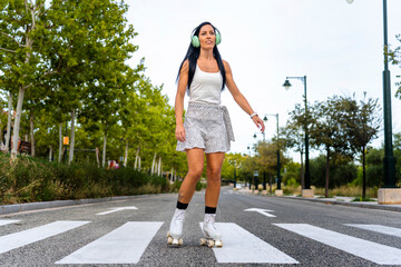 Happy middle-aged woman wearing dress smiling while rollerblading asphalt road in sunny day