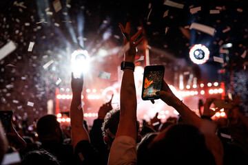 Crowd of people having fun while watching confetti fireworks at music festival.