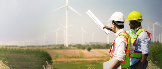 Wind turbine engineer. Male engineer maintains and controls wind turbine energy generation on the background of windmills. Concept of sustainable future. inspection work in wind turbine farms.