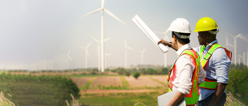 Wind turbine engineer. Male engineer maintains and controls wind turbine energy generation on the background of windmills. Concept of sustainable future. inspection work in wind turbine farms.