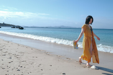 沖縄のビーチを裸足で歩く女子大生