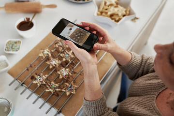 Red head woman taking picture of baked Christmas cookies