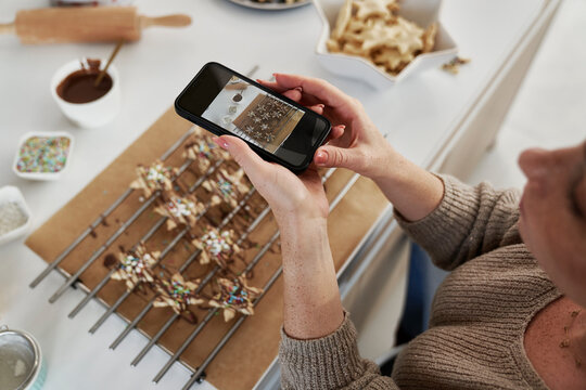 Red head woman taking picture of baked Christmas cookies