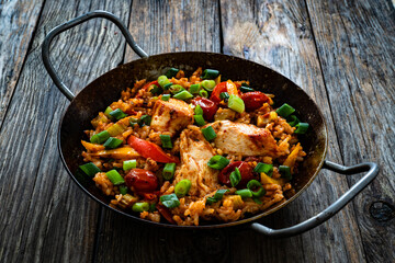 Jambalaya one pot dish - fried chicken breasts with white rice, tomatoes, bell pepper and celery on wooden table
