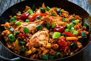 Jambalaya one pot dish - fried chicken breasts with white rice, tomatoes, bell pepper and celery on wooden table
