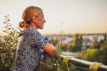 Beautiful woman enjoys standing on her balcony at sunset.