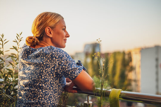 Beautiful woman enjoys standing on her balcony at sunset.