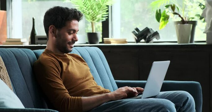 Cheerful Middle Eastern man engages in a video call while using his laptop. His warm smile and active participation highlight the positive and effective nature of remote communication.