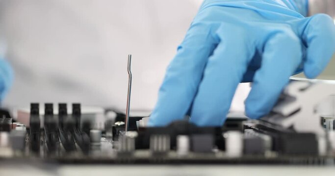 Gloved engineer inserts microcircuit into motherboard. Computer components assembly concept